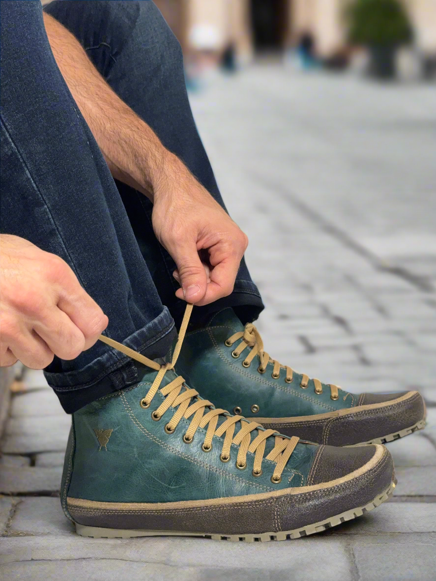 Person tying the laces of a blue boot on a white background