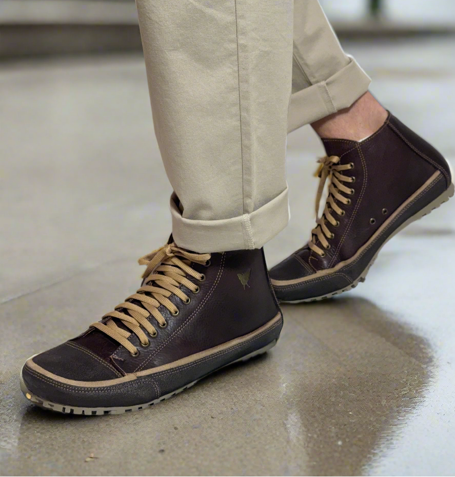 Person wearing black boots with tan laces on a white background