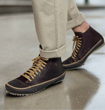Person wearing black boots with tan laces on a white background